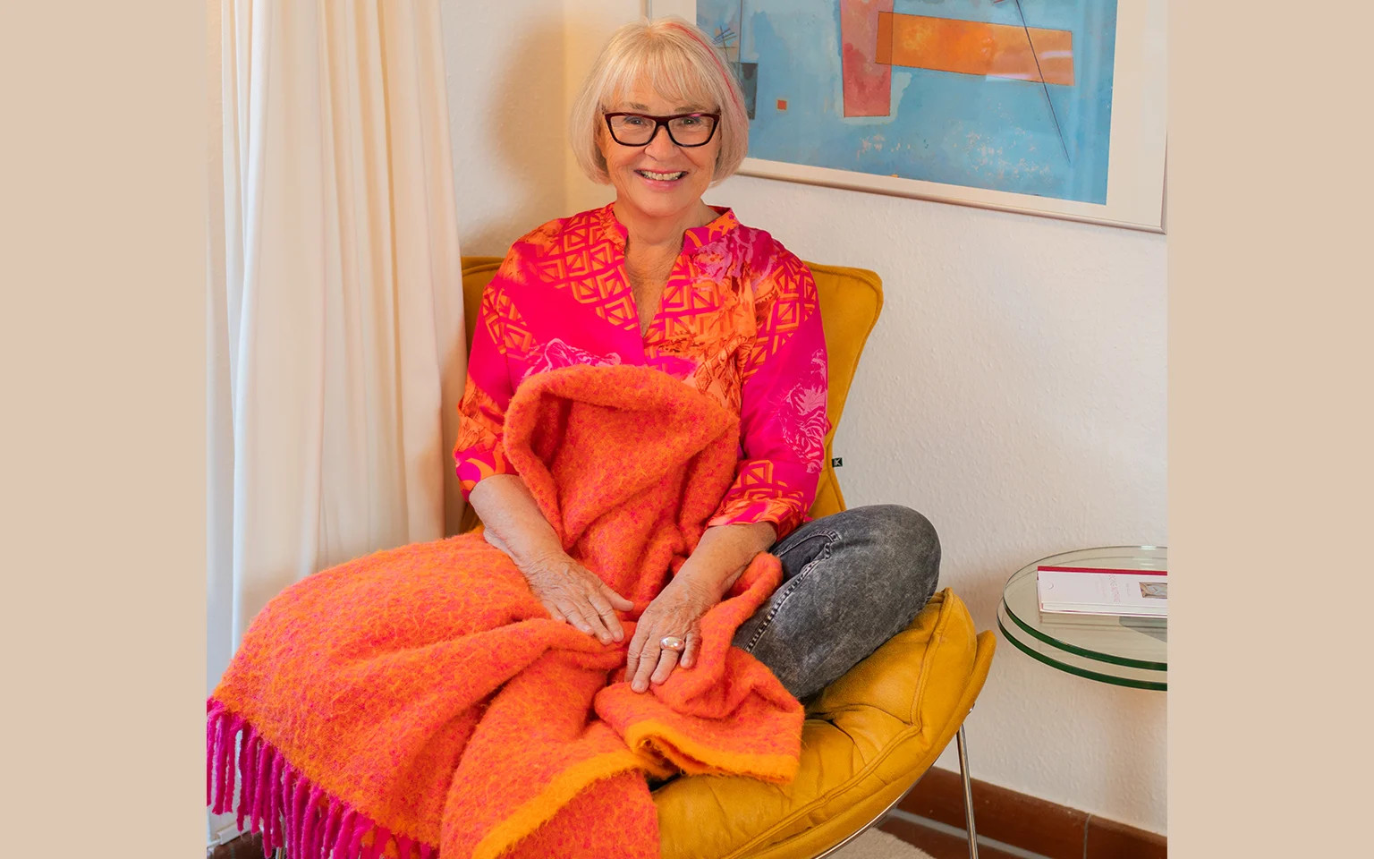 Ute Weisshaar, auf einem Stuhl sitzend, lachend